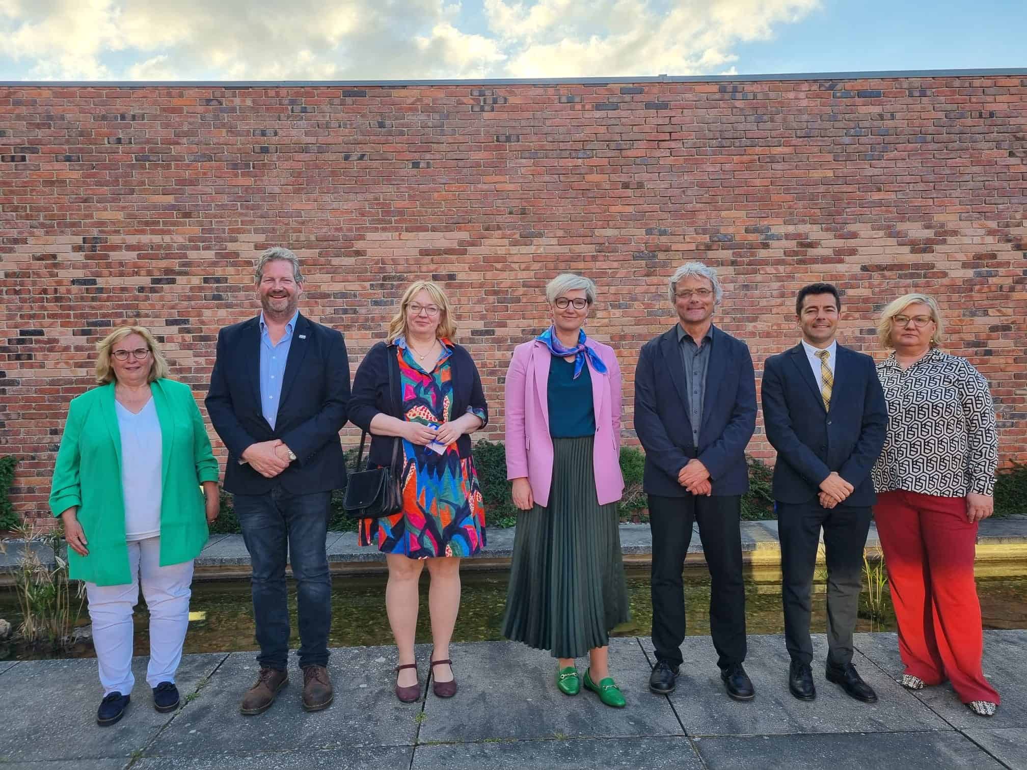 Diverse-university-group-photo-people-standing-outdoor-brick-wall-equality-inclusion-learning-conference.
